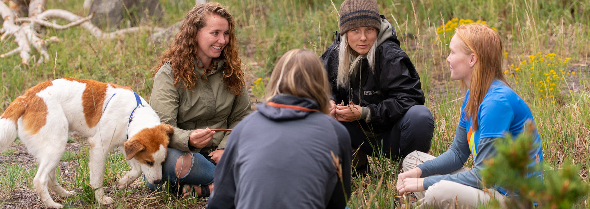 A group of women and a therapy dog sit in a circle, demonstrating a holistic therapeutic approach that uses nature, peer support, and animal-assisted therapy to create a safe space for healing.