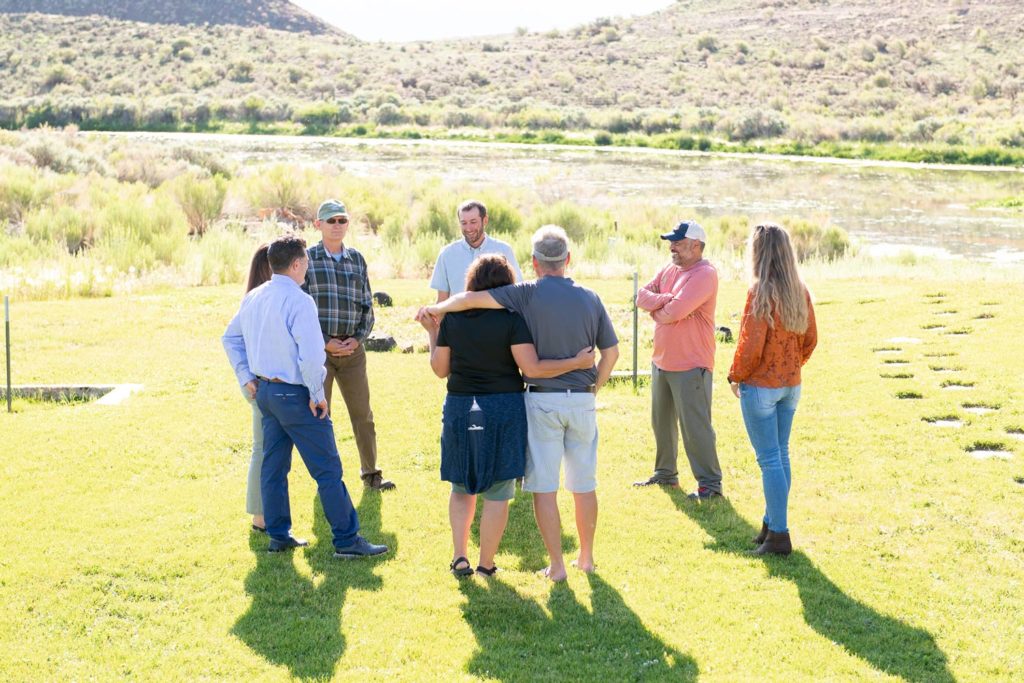 A group of adults form a supportive circle during a family or group therapy session, demonstrating a community-based therapeutic approach focused on healing relationships and building empathy.