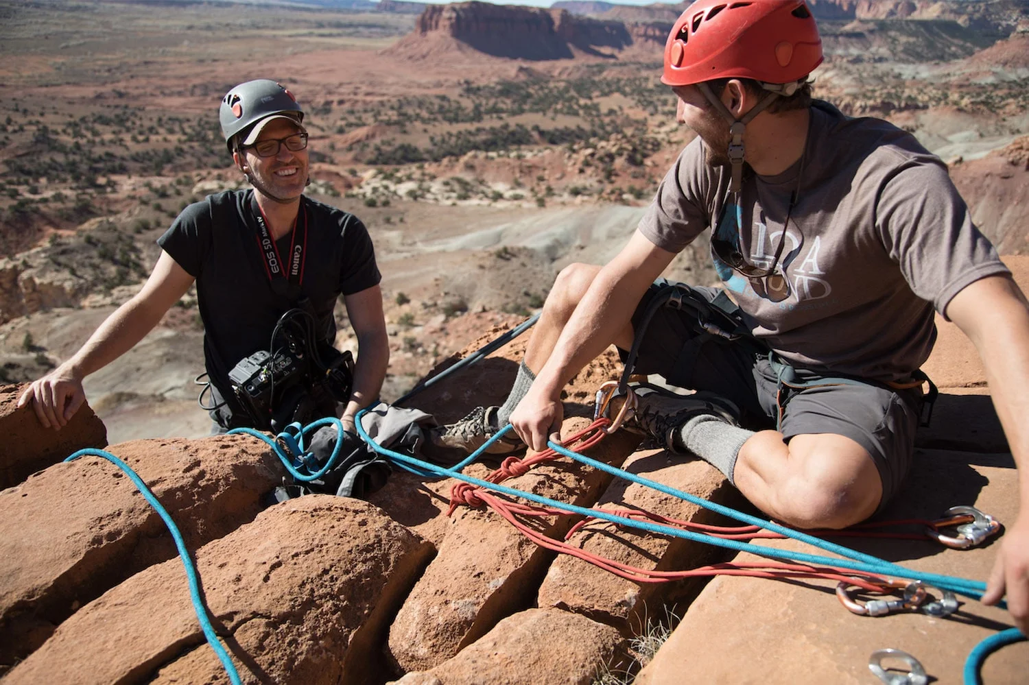 An expert guide provides instruction on climbing safety and rope management to a client, answering common questions and building confidence before an adventure therapy activity.