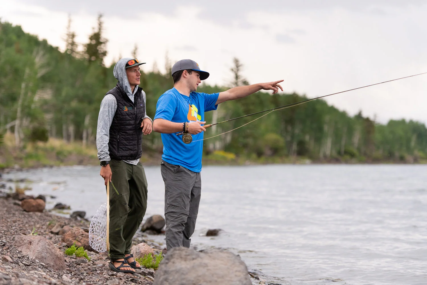 A mentor instructs a young man on fly fishing, an activity that teaches guiding principles such as patience, focus, and mindful action as part of a men's mental health and recovery program.