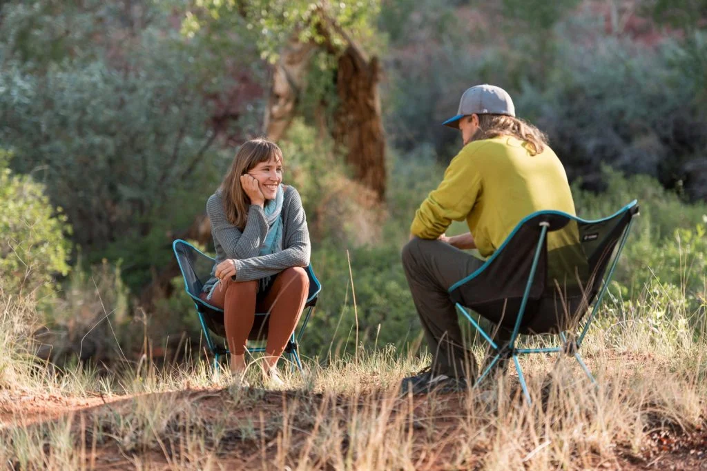 A client smiles warmly while listening to her therapist during an individual outdoor counseling session, demonstrating a therapeutic approach centered on trust, safety, and building a strong rapport.