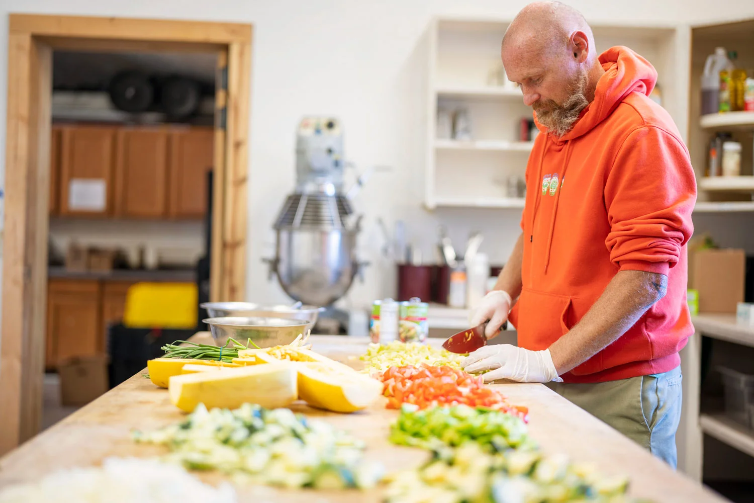 A man mindfully prepares fresh vegetables, part of a holistic healing approach that emphasizes the importance of nutrition and life skills for lasting mental health and addiction recovery.