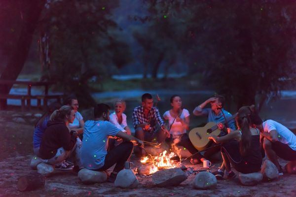 Young adults gathered around a campfire with music and peer support activities during outdoor recovery treatment at Legacy Outdoor Adventures in Utah.