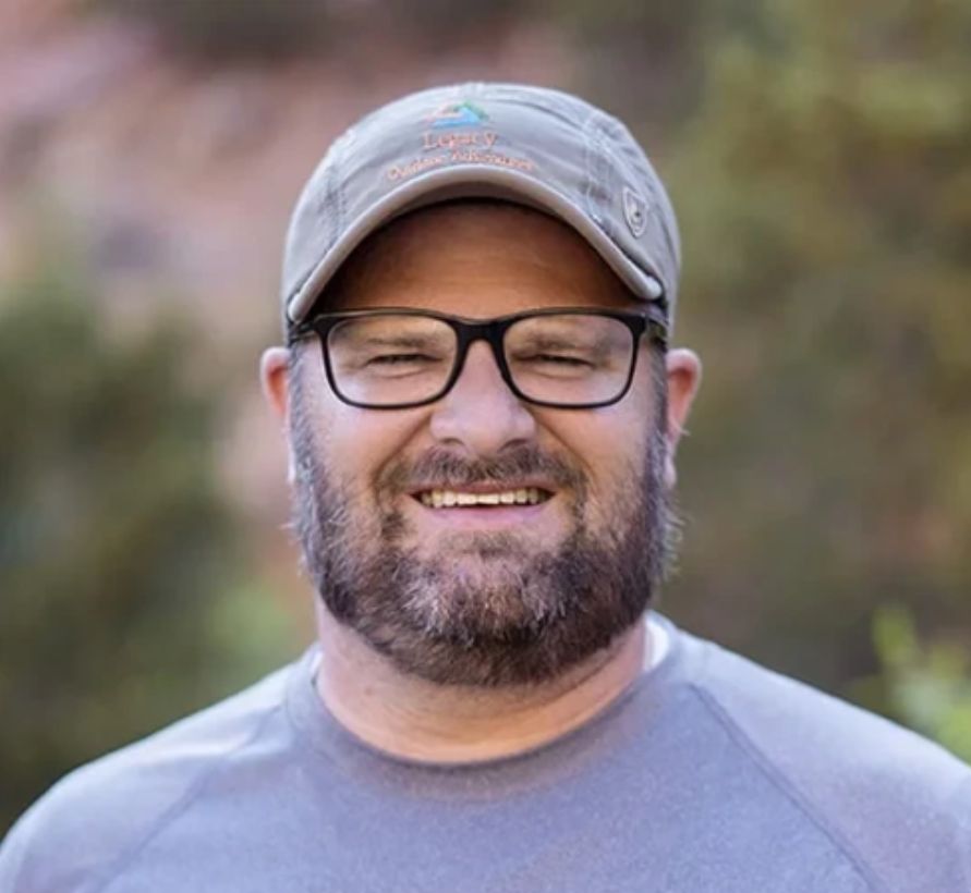 Portrait of a team member wearing a Legacy Outdoor Adventures hat, representing trauma-informed care and guidance.