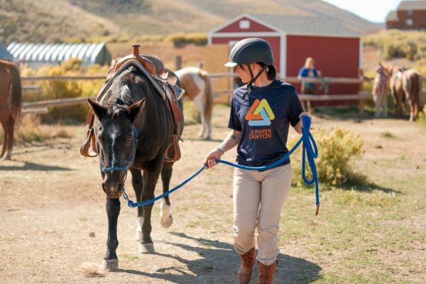 Client leading a horse across the Legacy Outdoor Adventures ranch during an equine-assisted residential addiction treatment program in Texas.