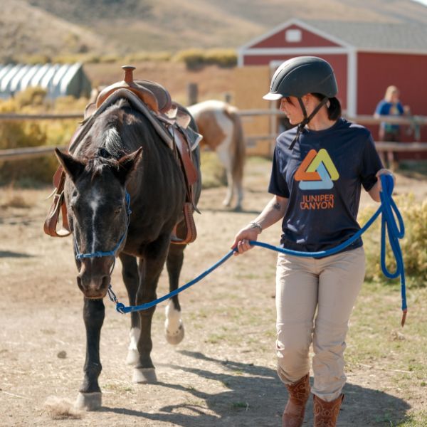 Client leading a horse across the Legacy Outdoor Adventures ranch during an equine-assisted residential addiction treatment program in Texas.