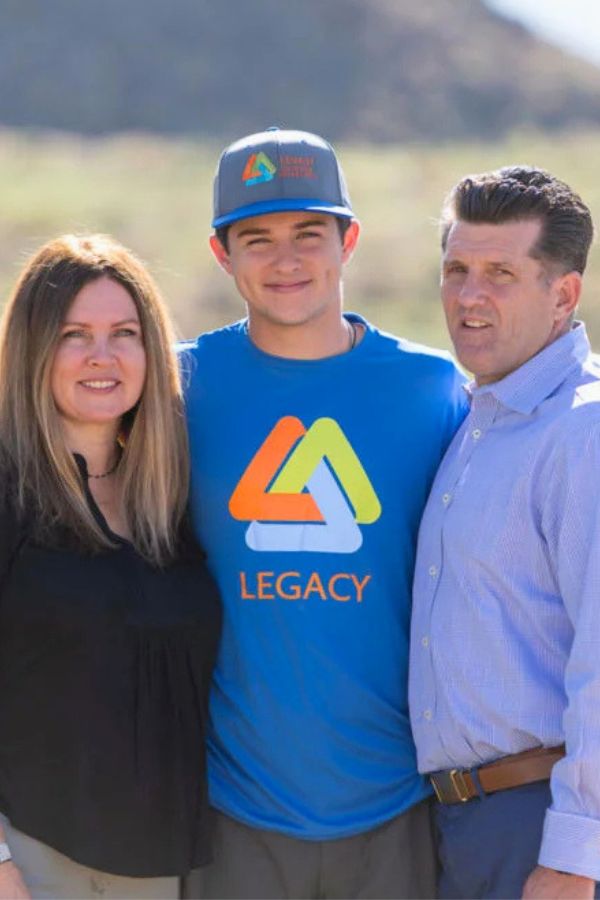 A group of three people standing together in a natural setting, emphasizing the family attachment pillar of the program.